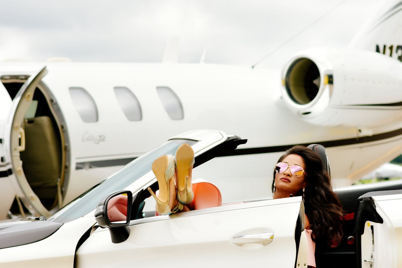 services-02 Luxurious travel scene with a woman in a convertible beside a private jet.